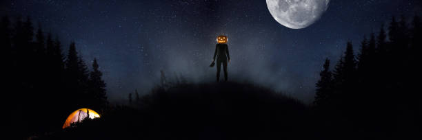 istock Halloween theme: scary maniac with pumpkin head in dark forest 1176591474