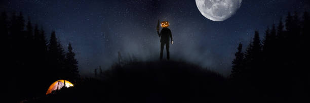 istock Halloween theme: scary maniac with pumpkin head in dark forest 1176591486