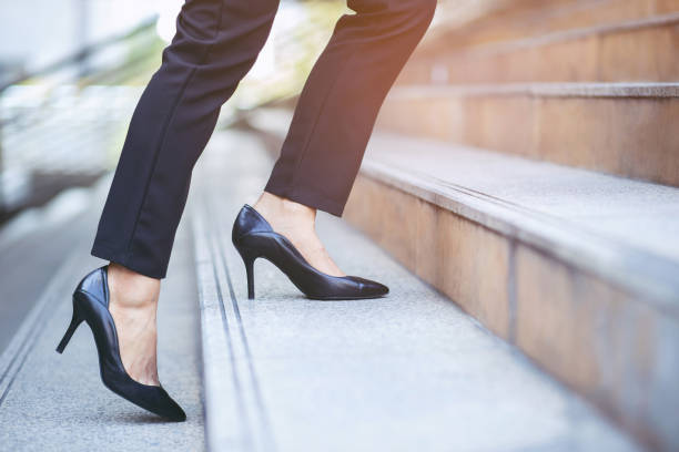 moderne geschäftsfrau arbeitende frau nah an den beinen gehen die treppe in der modernen stadt in der hauptverkehrszeit zu arbeiten im büro eine eile. am ersten morgen der arbeit. lassen sie platz zum schreiben von beschreibendem text - hoher absatz stock-fotos und bilder