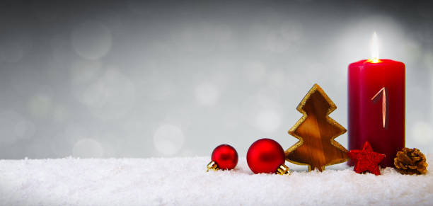 First Advent.Christmas background with Advent candle and red decoration.