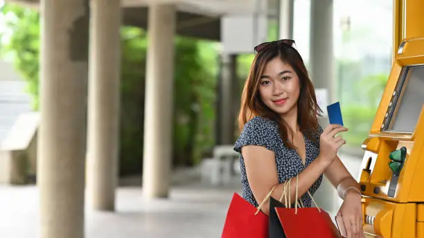 Young shopping girl and shopping bag holding credit card and ATM in shopping mall.