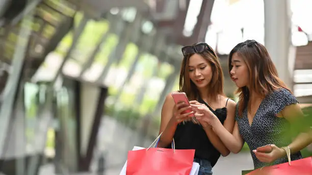 Two young woman looking at smartphone with shopping concept.