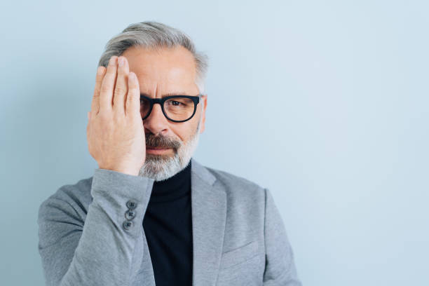Middle-aged man covering one eye with a hand
