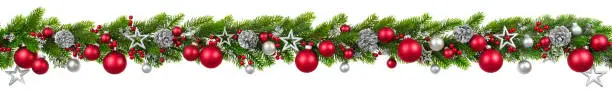 Extra wide Christmas border with hanging garland of fir branches, red and silver baubles, pine cones and other ornaments, isolated on white