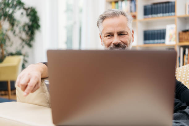 istock Happy man smiling as he uses his laptop 1176603192