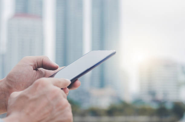 istock close up handsome man using hand typing smartphones and touch screen working search with app devices outdoor in city with sunrise and building background. 5G technology connecting the world. 1176604097