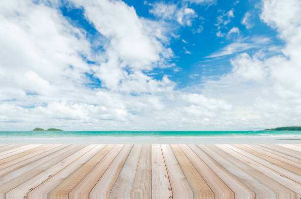 istock wood table with tropical beach and sea summer and blue sky with cloud background. beautiful floor copy space for design your products brand for ad. 1176604099