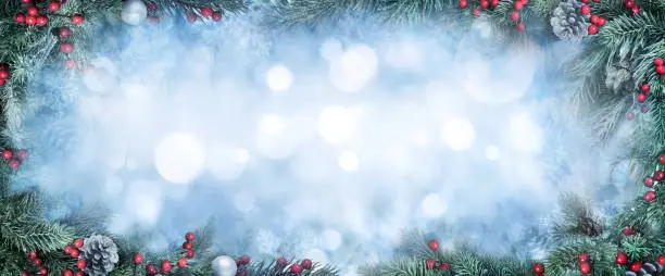 Christmas Background with frosty fir branches as a frame around blue bokeh copy space