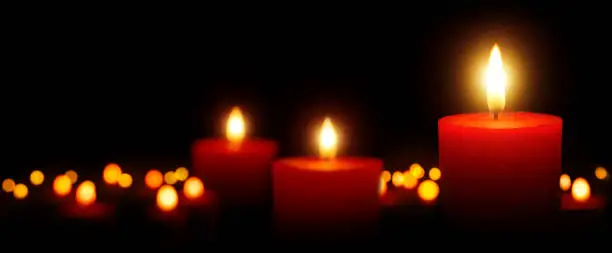 Burning candles gently glowing in the dark: tranquil low-key shot with shallow depth of field; for Christmas, spiritual and many more uses
