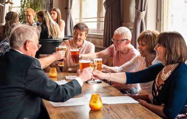 Friends together in a British pub Friends touching glasses as they catch up together. english cuisine stock pictures, royalty-free photos & images
