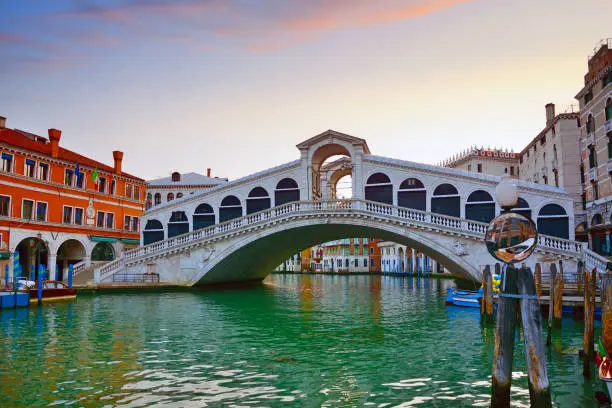 Rialto Bridge over Grand Canal at sunrise in Venice, Italy. Composite photo