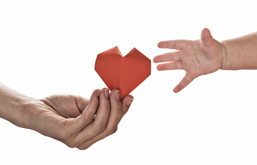 Baby to takes red paper heart from mom's hands. Concept of love, care, adoption. Color, isolated image.