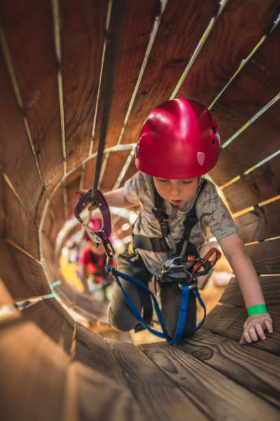 Cute little boy crawls through the wooden pipe in an adventure park Cute little boy crawls through the wooden pipe in an adventure park canopy tour photos stock pictures, royalty-free photos & images