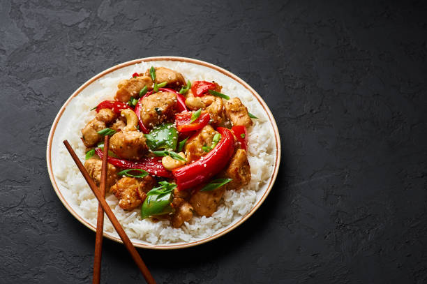 istock Schezwan Chicken or Dragon Chicken with basmati rice at black slate background. Szechuan Chicken is popular indo-chinese spicy dish with chilli peppers, chicken and vegetables. 1176608282