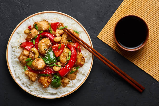 istock Schezwan Chicken or Dragon Chicken with basmati rice at black slate background. Szechuan Chicken is popular indo-chinese spicy dish with chilli peppers, chicken and vegetables. 1176608323