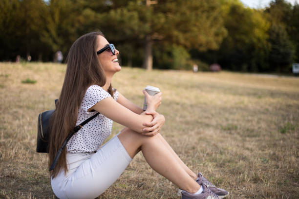 istock Happy woman sitting on the grass and drinking coffee 1176609879