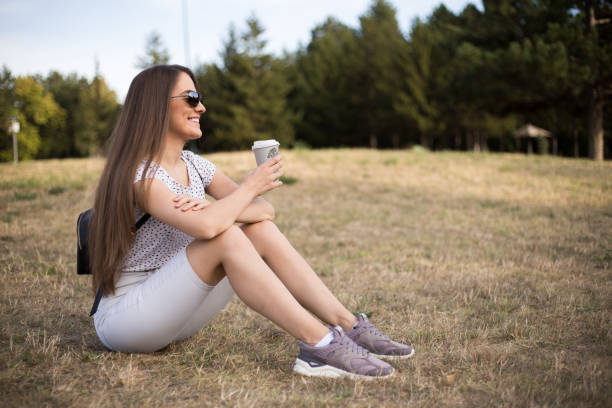 istock Happy woman sitting on the grass and drinking coffee 1176609954