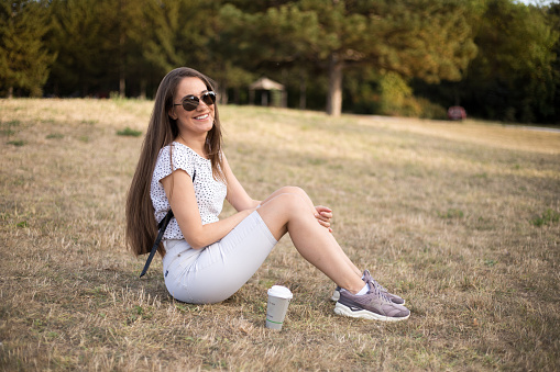 Young woman enjoying her coffee break in the park
