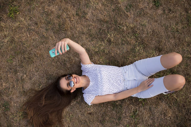 istock Young woman taking selfies while lying on the grass 1176610195