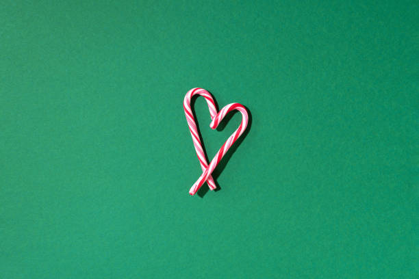 cuore di canna da zucchero di natale su sfondo verde con spazio di copia. vista dall'alto. amore, concetto di san valentino. biglietto di capodanno e natale - peppermint candy stick striped foto e immagini stock