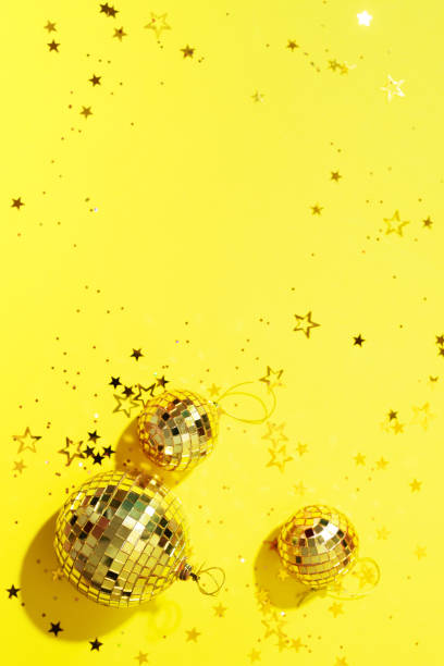 istock Creative Christmas concept. Shiny gold disco balls over yellow background. Flat lay, top view. New year baubles, star sparkles. Party time. Greeting card 1176612816