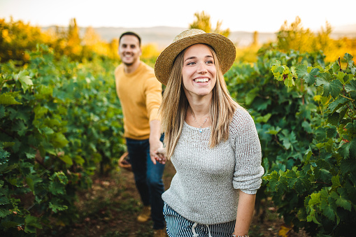 Woman Guiding Young Man by Holding His Hand Through Ripe Vineyard
