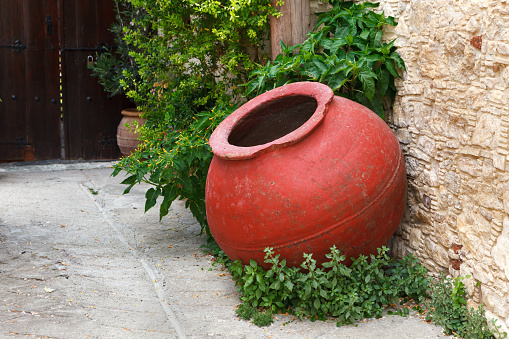 Large, old, red amphora on the street of the wine village. The design element of the street