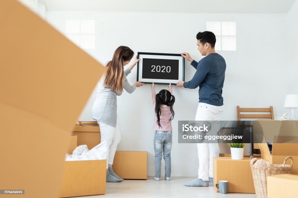 Happy Asian family picture holding frame during moving house together. Happy Asian family holding a picture frame during moving house together. 2019 to 2020, New Year concept. Family Stock Photo