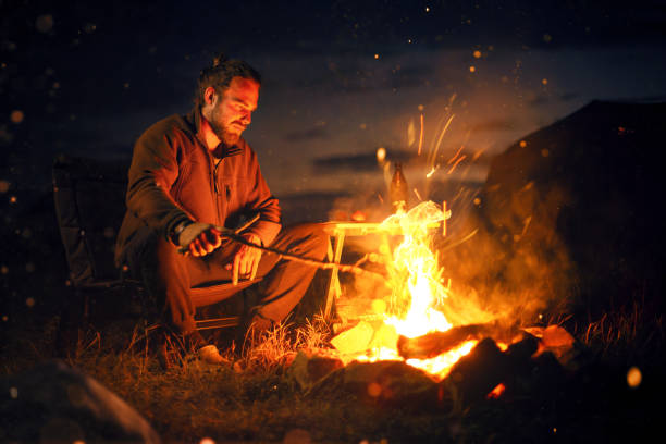 istock Man sitting next to a bonfire in the dark 1176619376