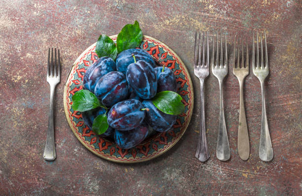 istock Plums fresh overhead arrangement with forks on plate painted background 1176620344