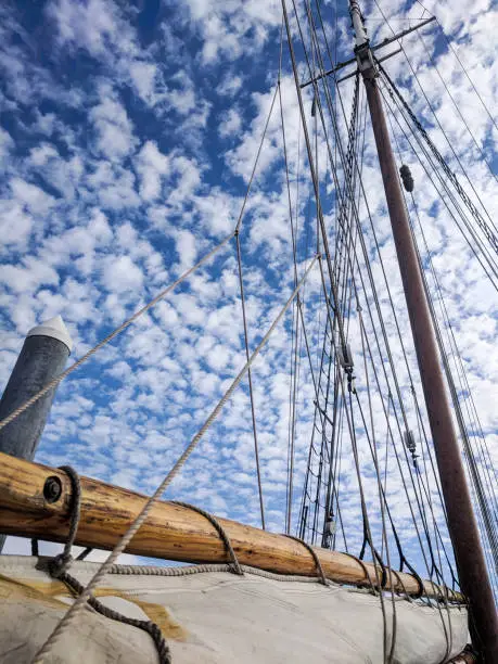 A traditional wooden sailing vessel beneath a blue sky speckled with clouds
