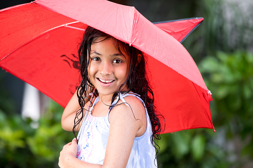 Happy girl holding a red umbrella on a rainy day