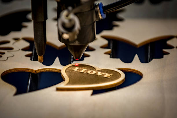 Laser engraving and cutting machine Close-up of laser engraving and cutting machine and just finished heart shaped wooden badge engraved image stock pictures, royalty-free photos & images