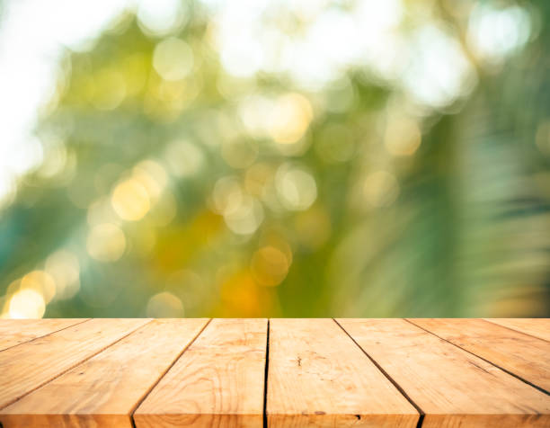 istock Real wood table top texture on blur fresh green garden background 1176624084