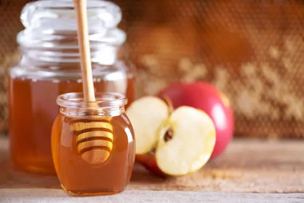 Apples with honey jar, honeycomb on grey background with copy space. Rosh hashanah jewish new year holiday celebration.