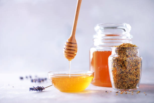 istock Bee pollen granules, honey jar with wooden dropper, honeycomb on grey backdrop. Copy space. Autumn harvest concept 1176629905