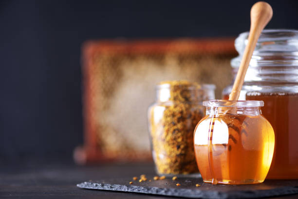 istock Bee pollen granules, honey jar with wooden dropper, honeycomb on dark backdrop. Copy space. Autumn harvest concept 1176630362