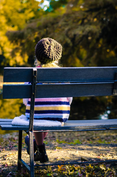istock little lonely child sitting in the bench alone 1176631626