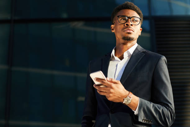 istock Pensive handsome young Afro-American businessman with beard using modern gadget on move 1176634387