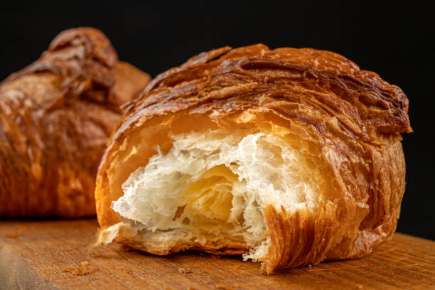 istock Tasty fresh croissant on a dark breadboard. Prepared bread on the kitchen table. Dark background. 1176634633