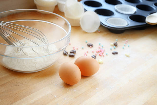 baking cupcakes with eggs, flour and muffin tin on a wooden kitchen board, copy space, selected soft focus, narrow depth of field