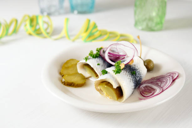 repas de gueule de bois, hareng mariné roulé, également appelé rollmops avec des oignons rouges, des cornichons et des câpres sur une table blanche avec des banderoles en papier, l'espace de copie - rollmops photos et images de collection