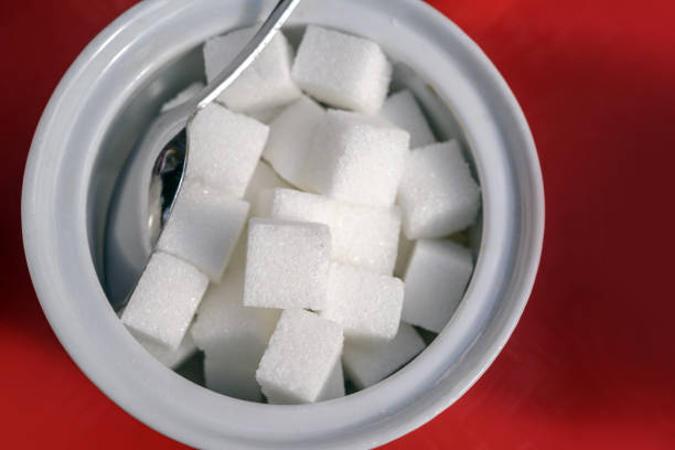istock sugar cubes and spoon in a white bowl on a red background, high angle view from above 1176636327