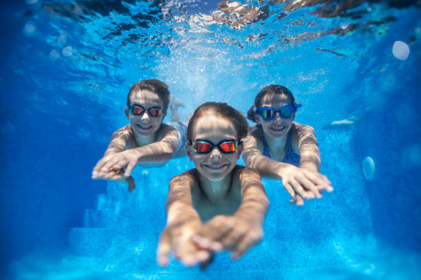 istock Three happy kids swimming underwater in pool 1176637818
