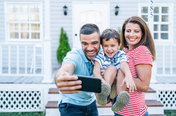 istock Parents with child having fun in front yard and taking selfie 1176638512