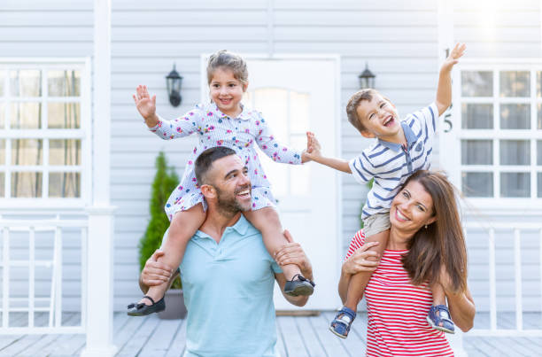 istock Parents having fun in front yard carrying children piggyback 1176638531