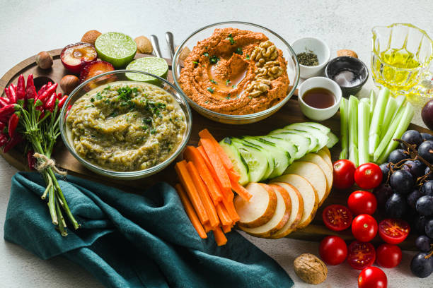 istock veggie serving table with snacks with vegetables, fruits, baba ganoush and dip or spread of roasted red pepper and nuts. healthy vegan food for celebration or friends. shot from above. copy space 1176640472
