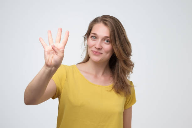 Pretty caucasian young woman holding up four fingers stock photo