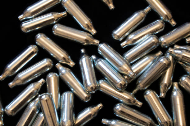 istock Nitrous Oxide Metal Bulb Canisters Recreational Drugs on Black Background 1176641817