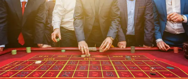 Photo of Group of people behind roulette gambling table in luxury casino banner